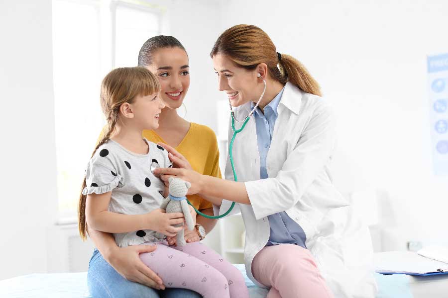 A caring moment at Bonneville Family Practice, where a woman holds a child's hand while a doctor conducts an examination.