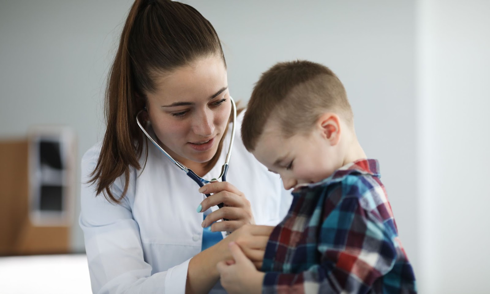 A woman in a family practice setting uses a stethoscope to examine a child,s chest, emphasizing primary care.