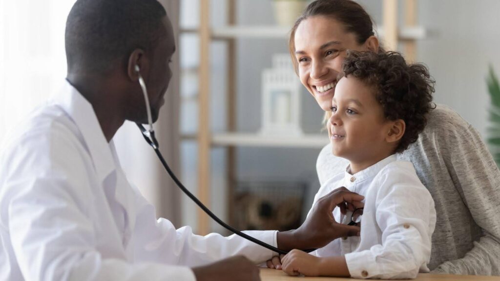 A doctor uses a stethoscope to examine a child during a medical check-up in a clinical setting