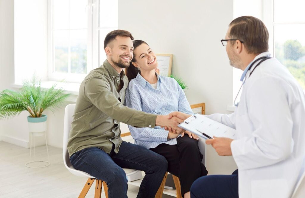 A man and woman sit together in a doctor office waiting for their appointment