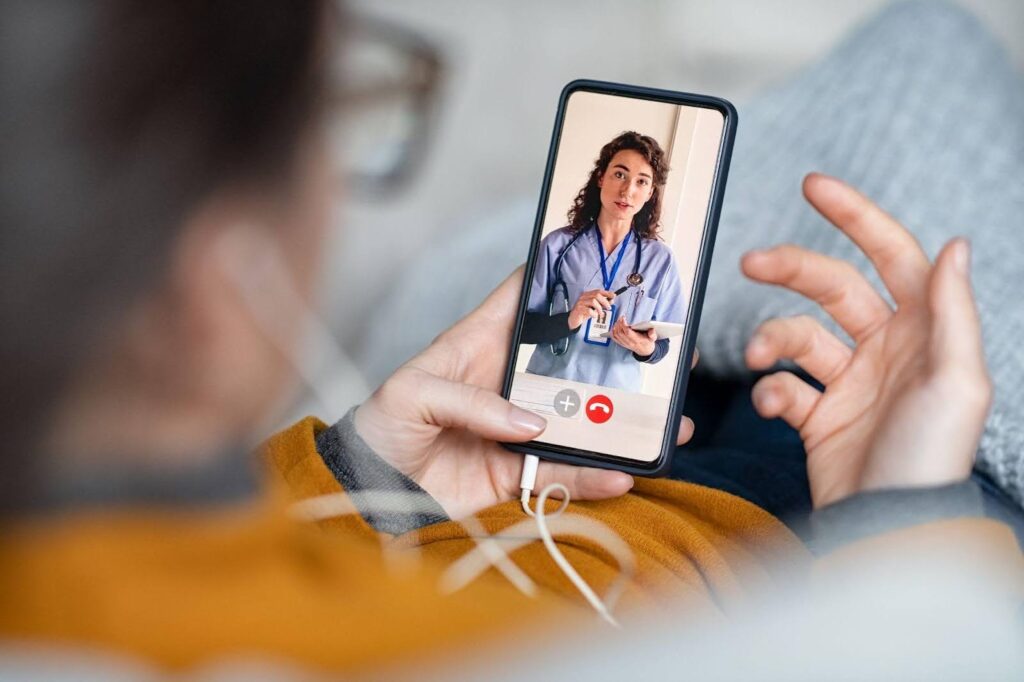 A woman video chatting with a doctor on her phone engaged in a virtual medical consultation