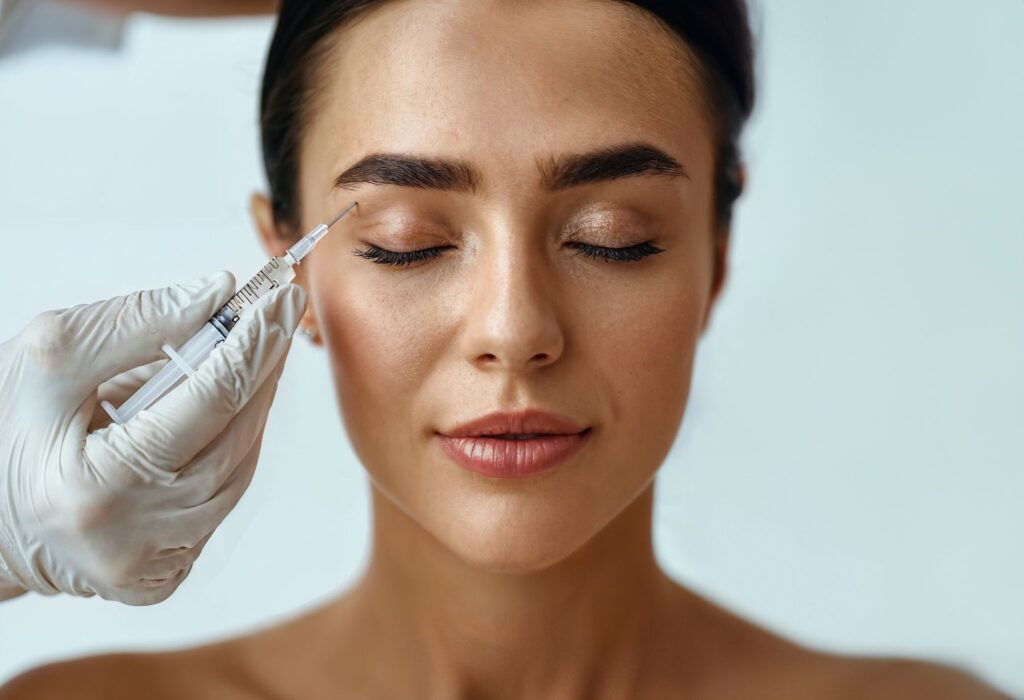 A person receiving a facial injection with a syringe by a gloved hand.