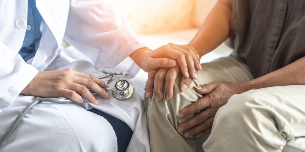 An elderly patient receives comfort as a doctor holds their hand symbolizing compassion and trust in healthcare