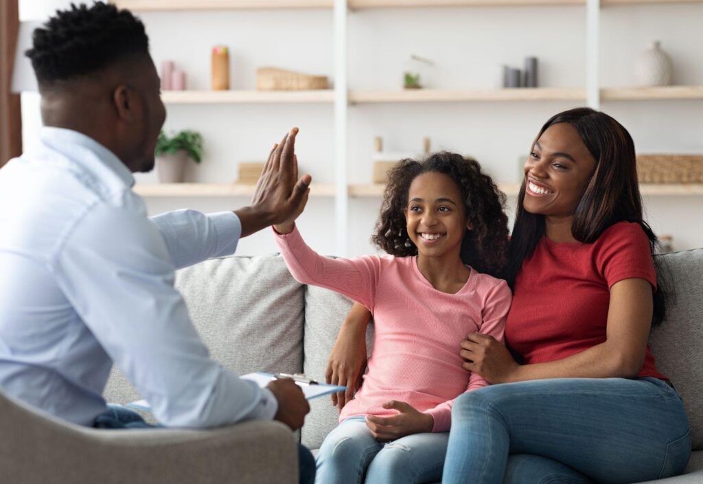 A joyful family on a couch all raising their hands in celebration together