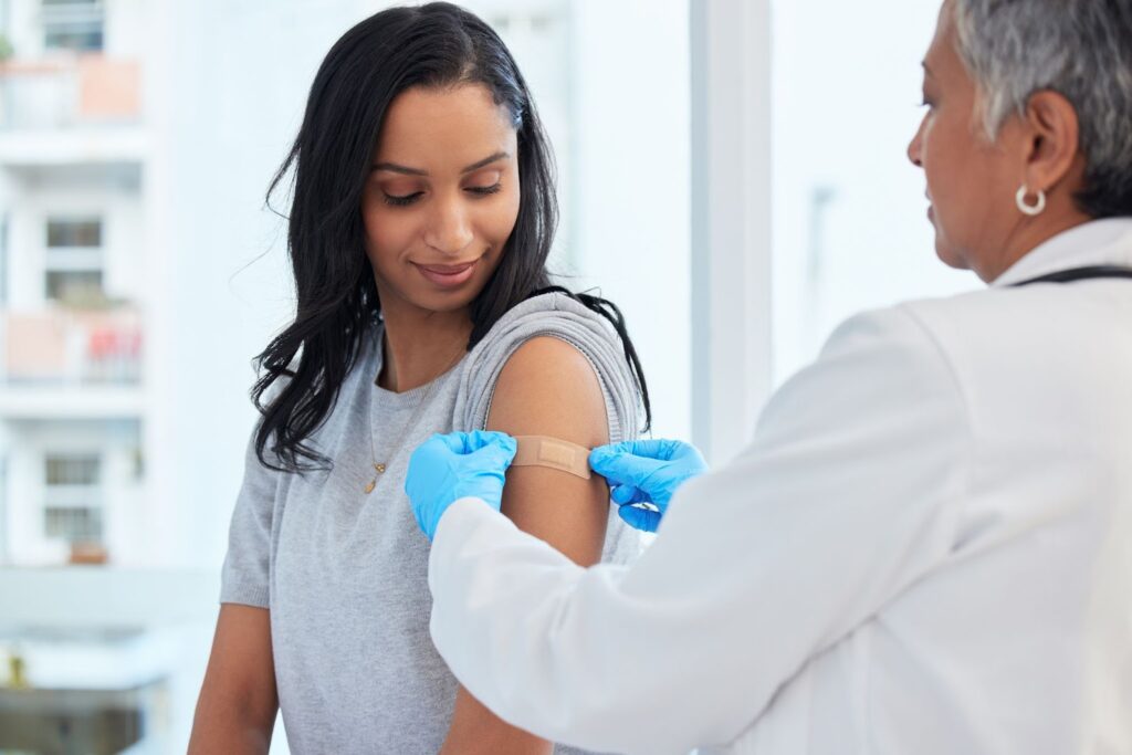 A woman receives an arm examination from a doctor, highlighting insurance-covered medical services.