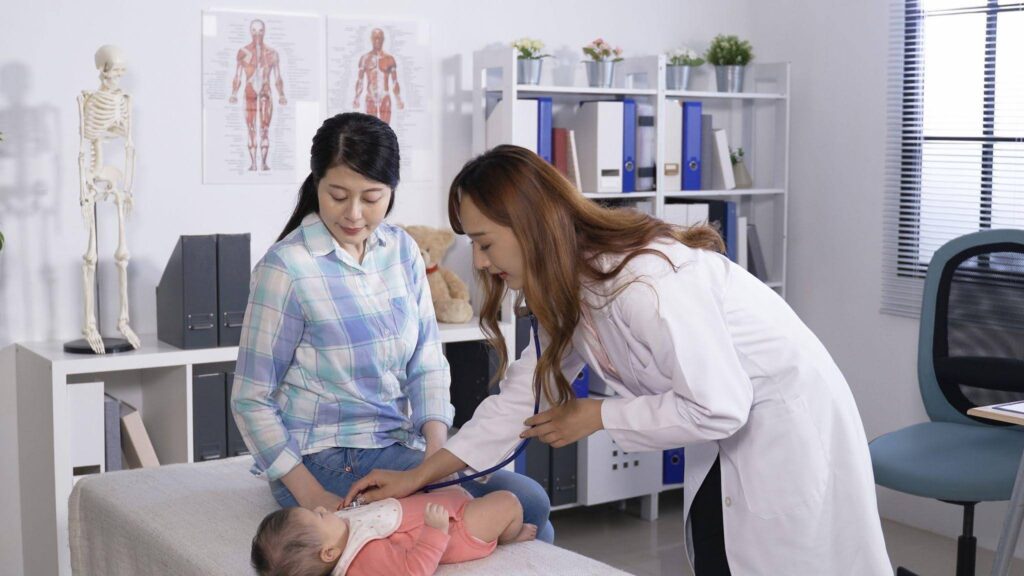In a doctor office a woman is carefully examining a baby highlighting a routine health check up