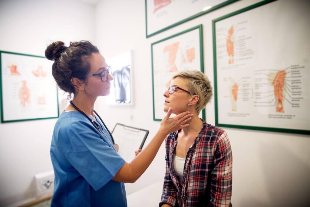 A woman inspects a woman neck appearing attentive and engaged in her examination