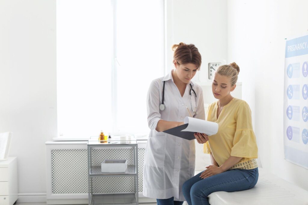 A woman and her doctor are sitting on a bed having a conversation about her health